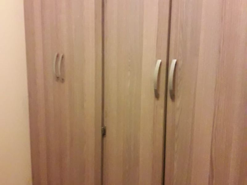 A close-up view of a built-in wooden wardrobe with metal handles in a bedroom.