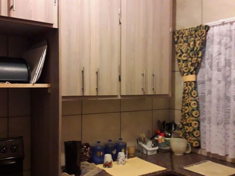 A functional kitchen featuring light wood-tone cabinetry, laminate countertops, and a tiled backsplash, providing a practical workspace for daily cooking needs.