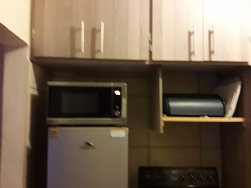 A compact kitchen area featuring built-in cabinetry, a microwave, and an electric stove, providing essential cooking functionality in a small footprint.