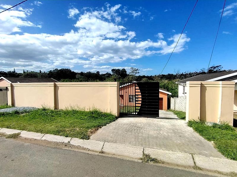 Front view of the property featuring a solid perimeter wall, a modern black sliding driveway gate, and a concrete driveway leading to the residence.