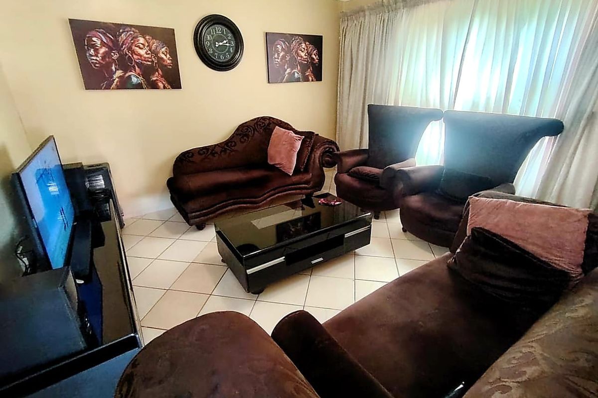 A comfortable living room featuring tiled flooring and decorative ceiling cornicing, providing a functional space for relaxation.