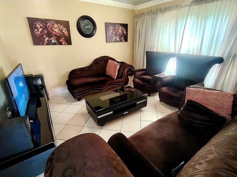 A comfortable living room featuring tiled flooring and decorative ceiling cornicing, providing a functional space for relaxation.