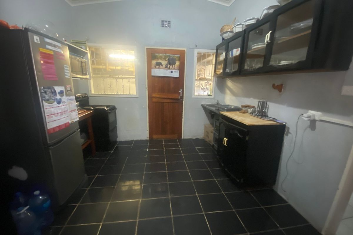 A functional kitchen featuring dark cabinetry, tiled flooring, and direct exterior access. The space would benefit from cosmetic updates to modernize the finishes.