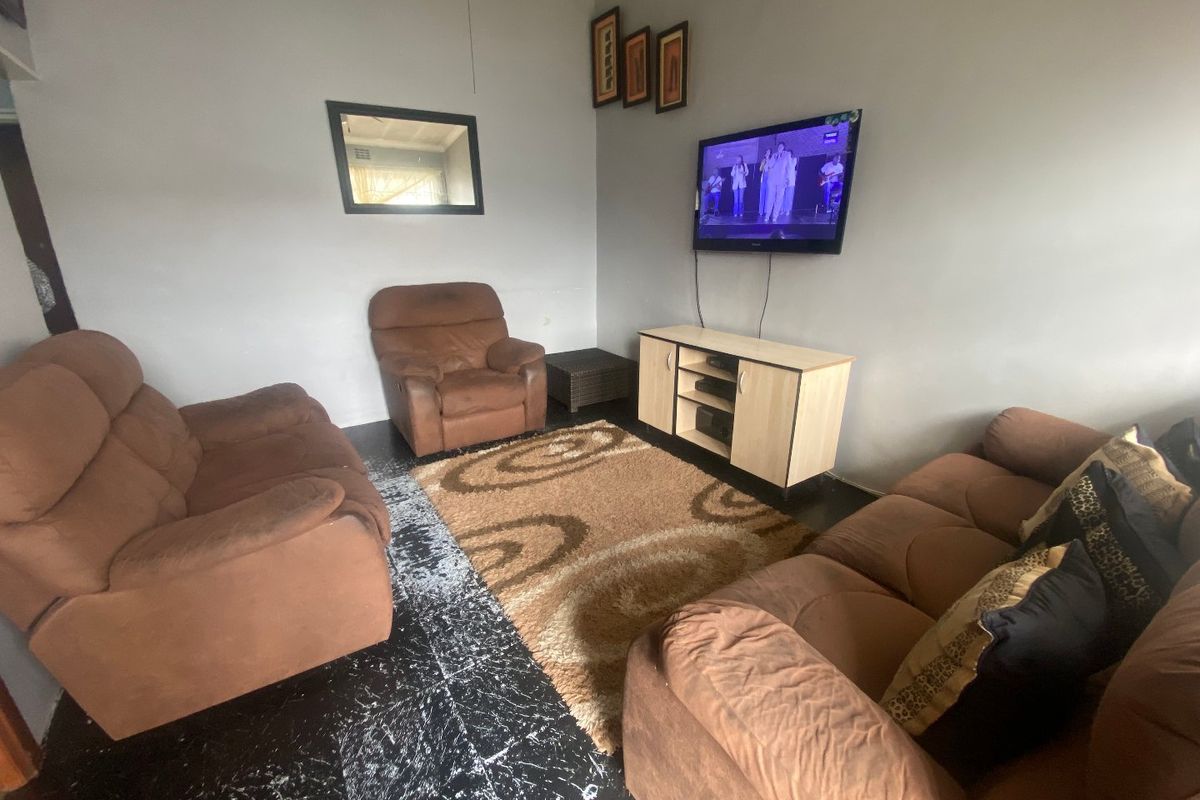 A living room featuring dark tiled flooring and neutral wall finishes, providing a functional space for relaxation.