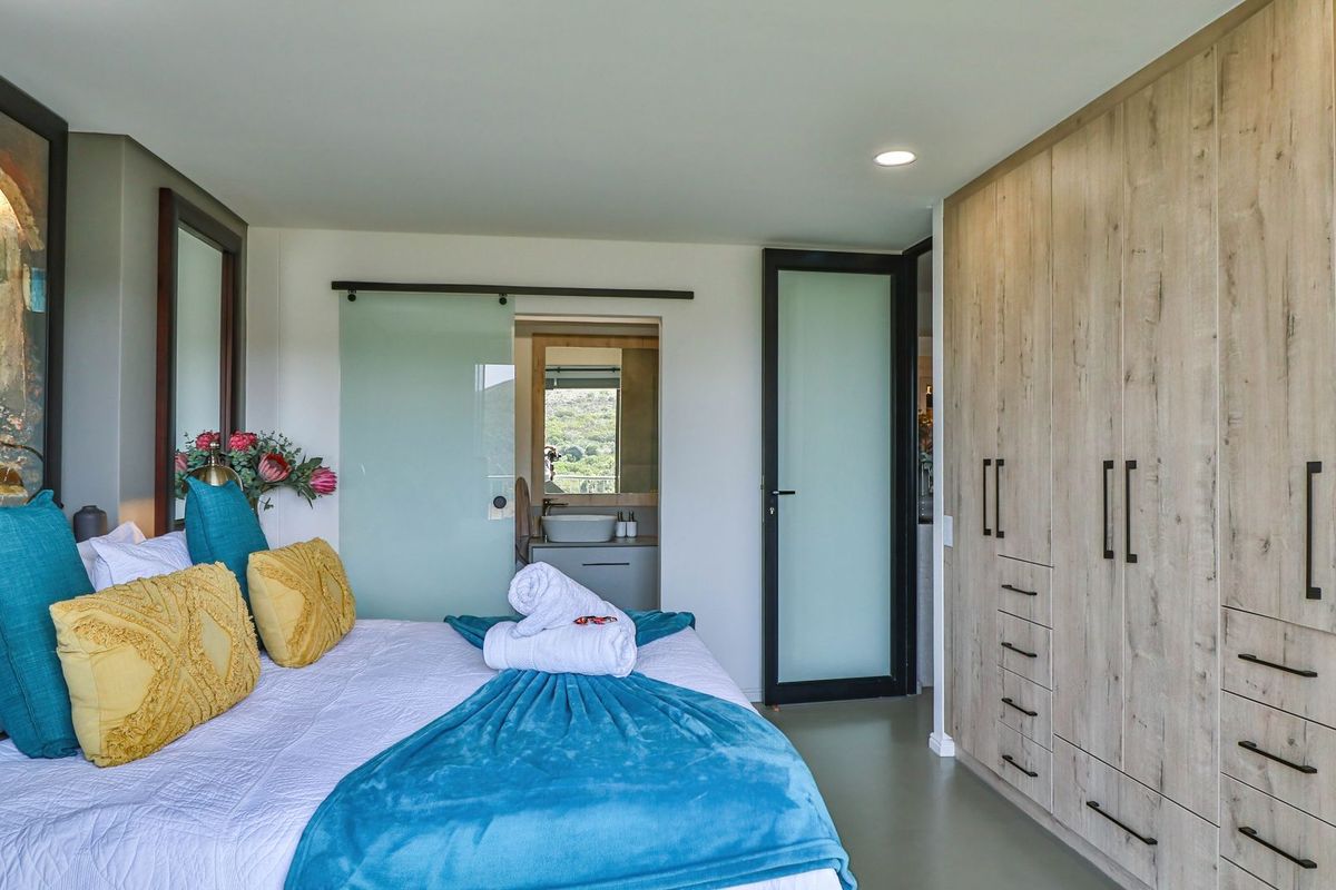 Modern bedroom featuring extensive built-in wooden cabinetry, recessed lighting, and a sliding glass door providing access to an en-suite bathroom.
