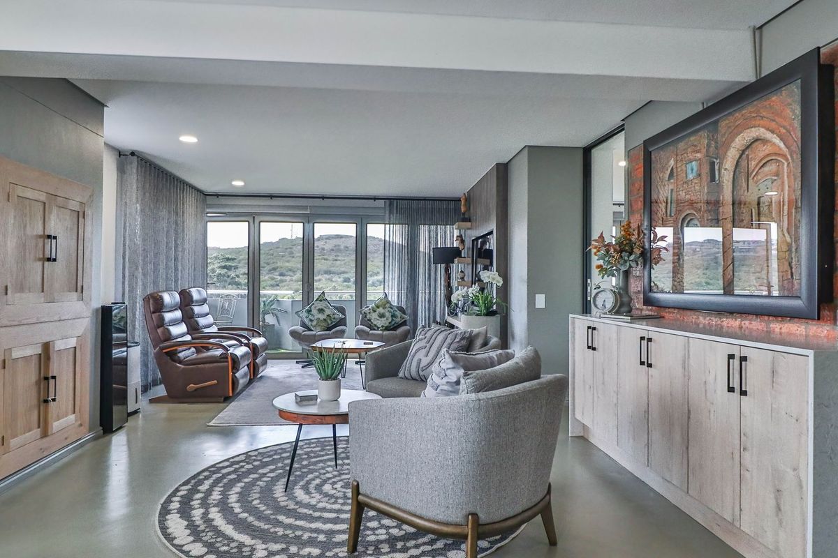 Modern open-plan living area featuring polished concrete floors, an exposed brick feature wall, custom built-in cabinetry, and large sliding doors leading to a balcony.