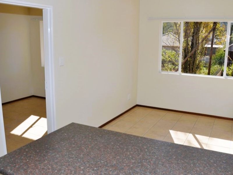 An empty open-plan living area featuring tiled flooring, a granite countertop, and a window with natural light.