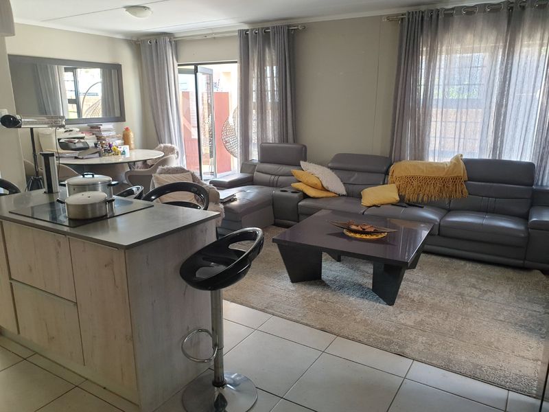 Open-plan living area featuring a kitchen island with a built-in hob, tiled flooring, and sliding glass doors leading to the outdoor space.