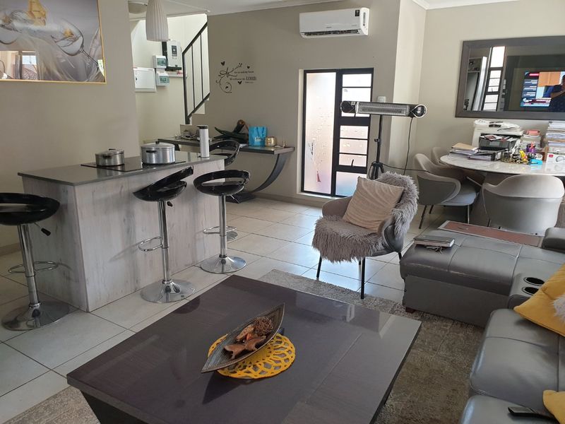 Open-plan living area featuring a kitchen island with a built-in hob, tiled flooring, and a split-system air conditioner.