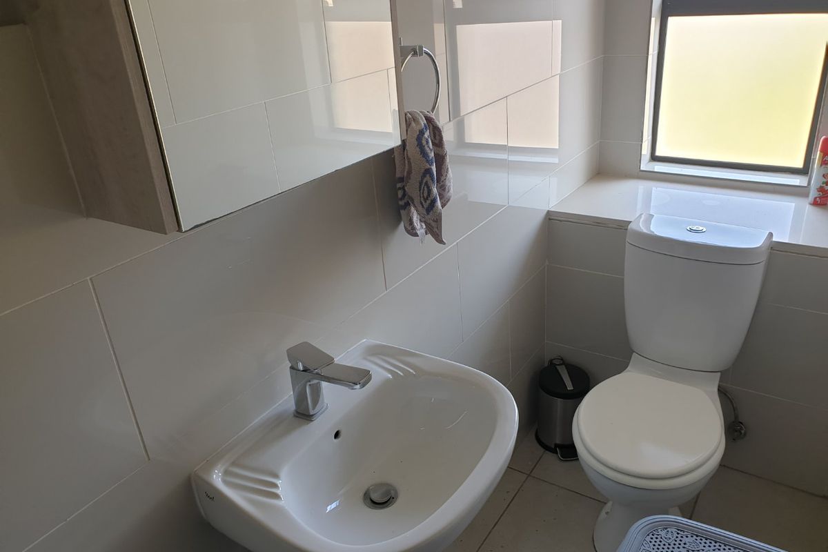 A clean and functional bathroom featuring a pedestal basin, chrome mixer tap, toilet, and modern tiled finishes.