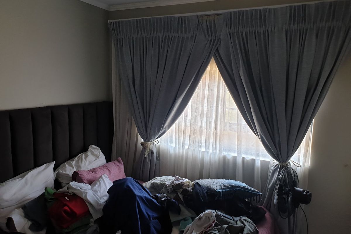 A bedroom featuring a window with installed curtain tracks and drapes, providing natural light to the space.