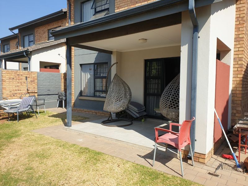 A covered patio area with tiled flooring, providing direct access to the garden and main living space through a sliding glass door.