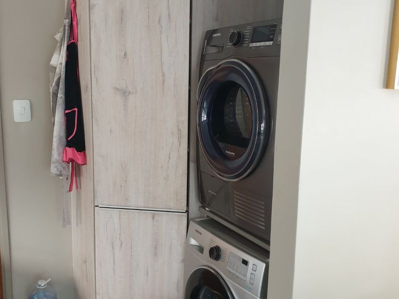 A compact laundry area featuring built-in cabinetry and tiled flooring, designed for efficient appliance placement.
