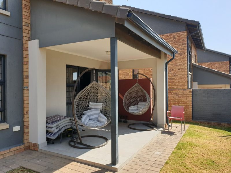 A covered patio area featuring tiled flooring and brick exterior walls, providing a functional outdoor space for relaxation.