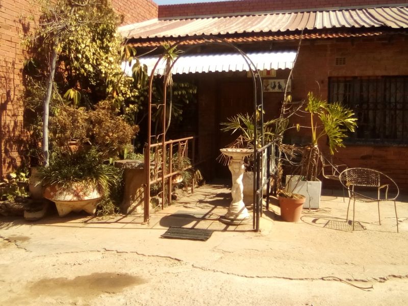 Front exterior view of an industrial property featuring a brick facade, roller shutter door, and a concrete driveway with visible surface wear.