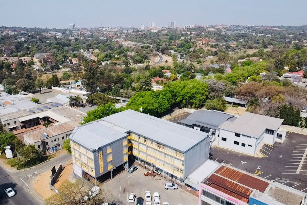 Aerial view of a commercial property complex featuring multi-story office buildings, paved parking areas, and surrounding urban landscape.