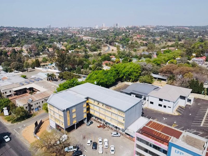 Aerial view of a commercial property complex featuring multi-story office buildings, paved parking areas, and surrounding urban landscape.