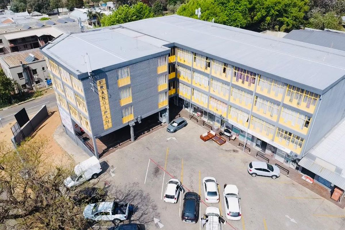 Aerial view of a multi-story commercial building featuring a paved parking lot and metal roofing.