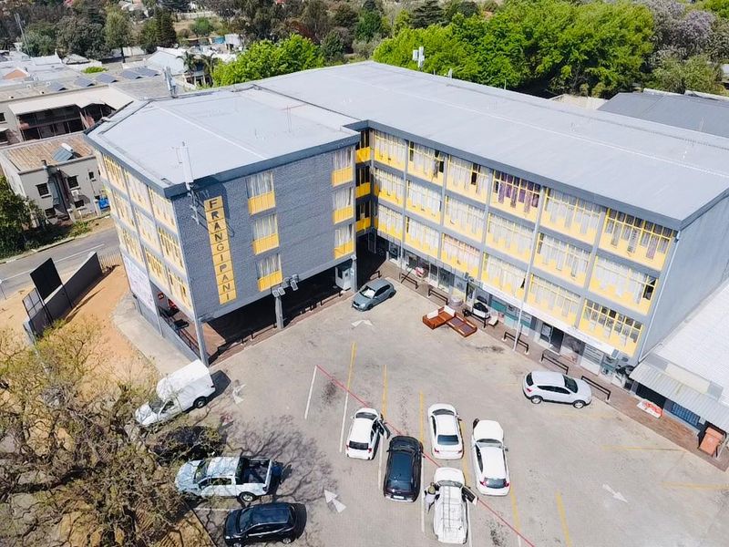 Aerial view of a multi-story commercial building featuring a paved parking lot and metal roofing.