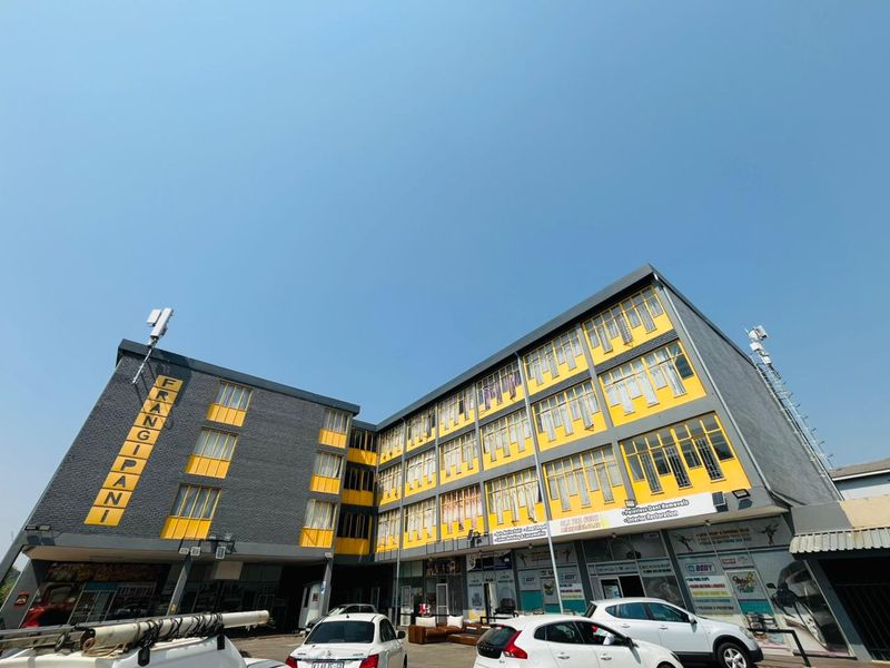 A multi-story commercial building featuring a yellow and grey facade with prominent signage and ground-level retail or workshop spaces.