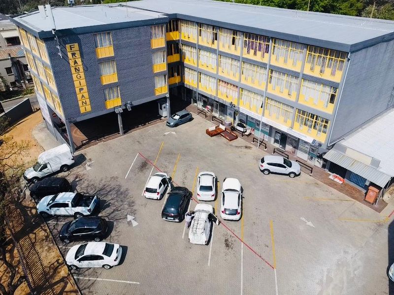 Aerial view of a multi-story commercial building featuring a paved parking lot and exterior facade with yellow and grey finishes.