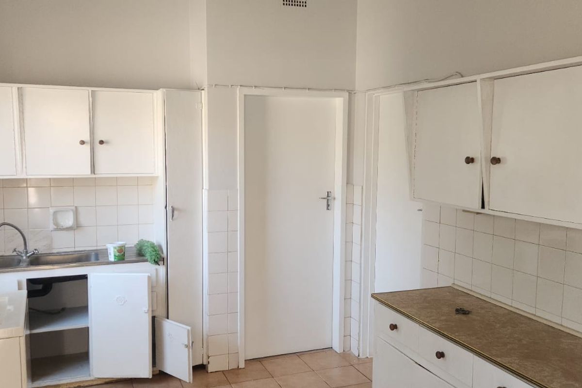 A dated kitchen featuring white built-in cabinetry, tiled backsplash, and laminate countertops, offering a blank canvas for a modern renovation.