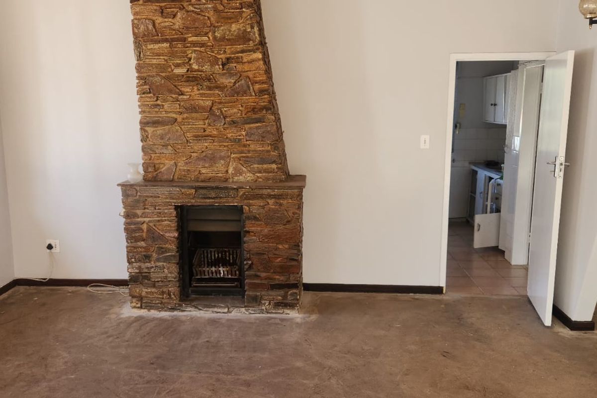 Spacious living room featuring a prominent stone fireplace and an arched doorway leading to the kitchen area.