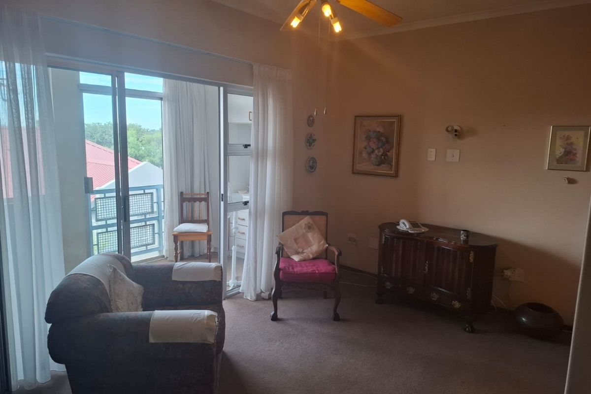 A living room area featuring carpeted flooring, a ceiling fan, and a sliding glass door providing access to an outdoor balcony.