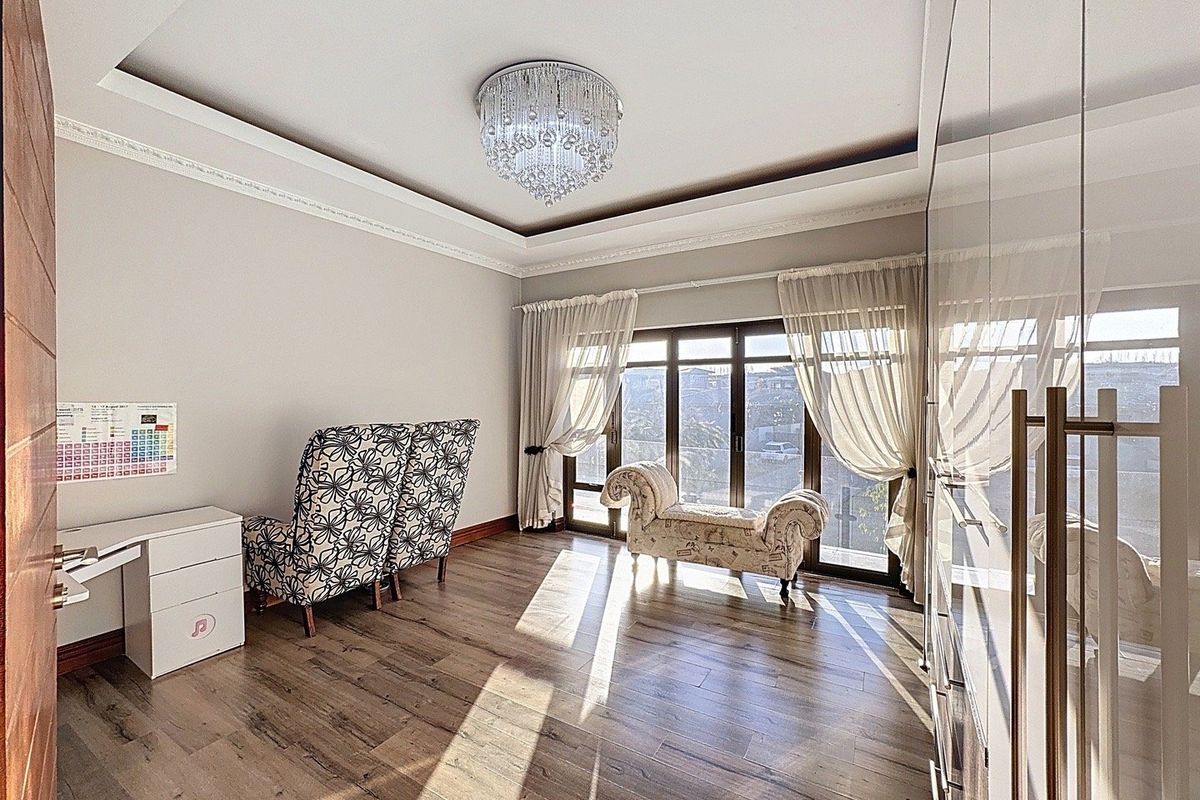 A bright bedroom featuring a tray ceiling with a crystal chandelier, built-in wardrobes, and sliding glass doors leading to an outdoor view.