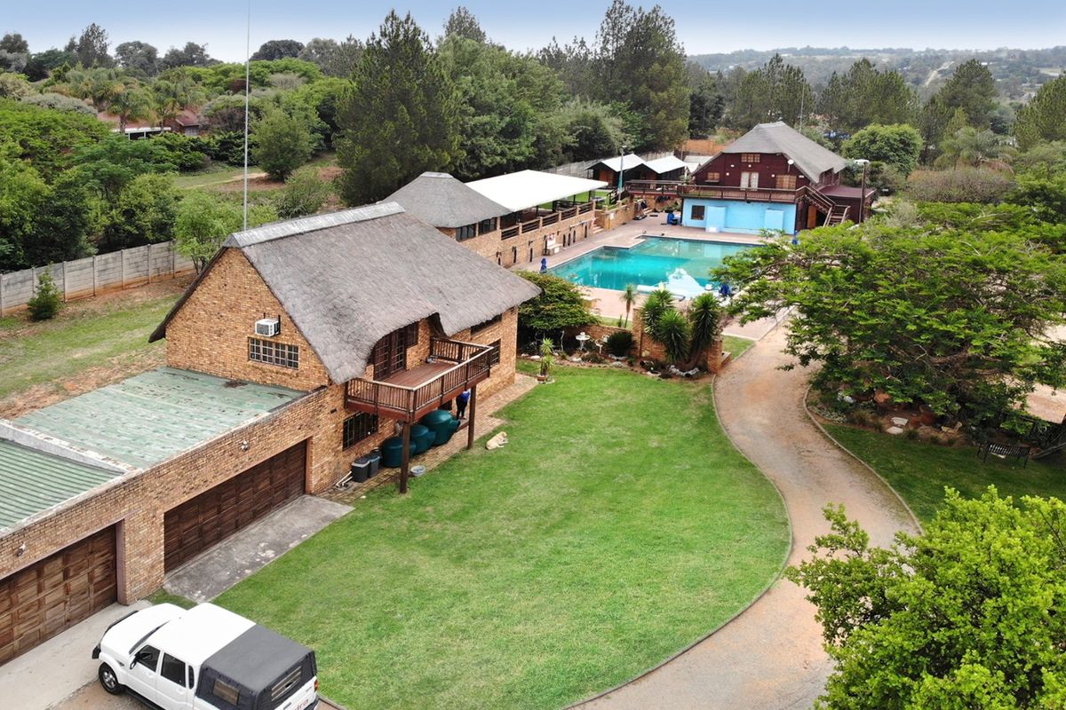 Aerial view of a commercial property featuring multiple brick buildings with thatched roofs, a swimming pool, and extensive landscaped grounds.