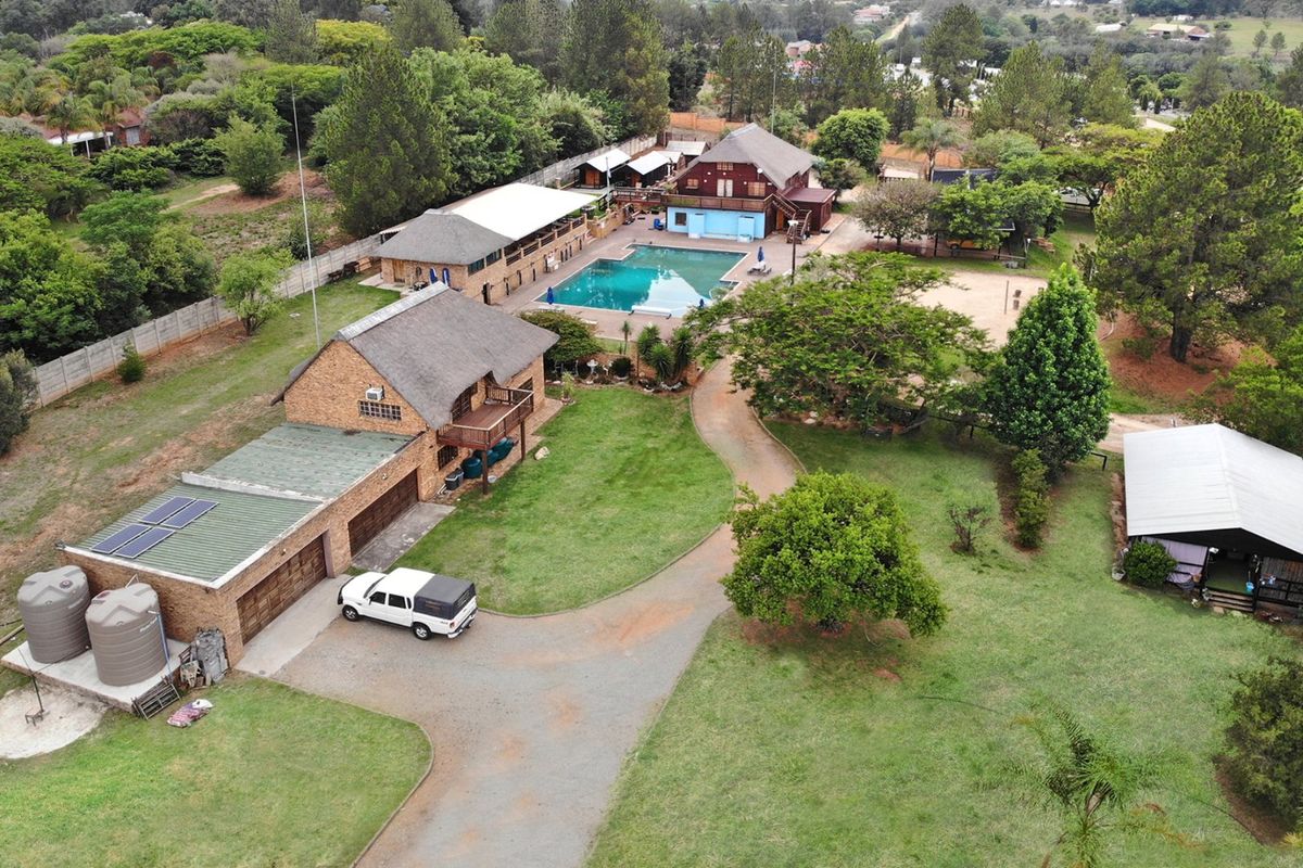 Aerial view of a commercial property featuring multiple buildings, a swimming pool, extensive grounds, water storage tanks, and a paved driveway.