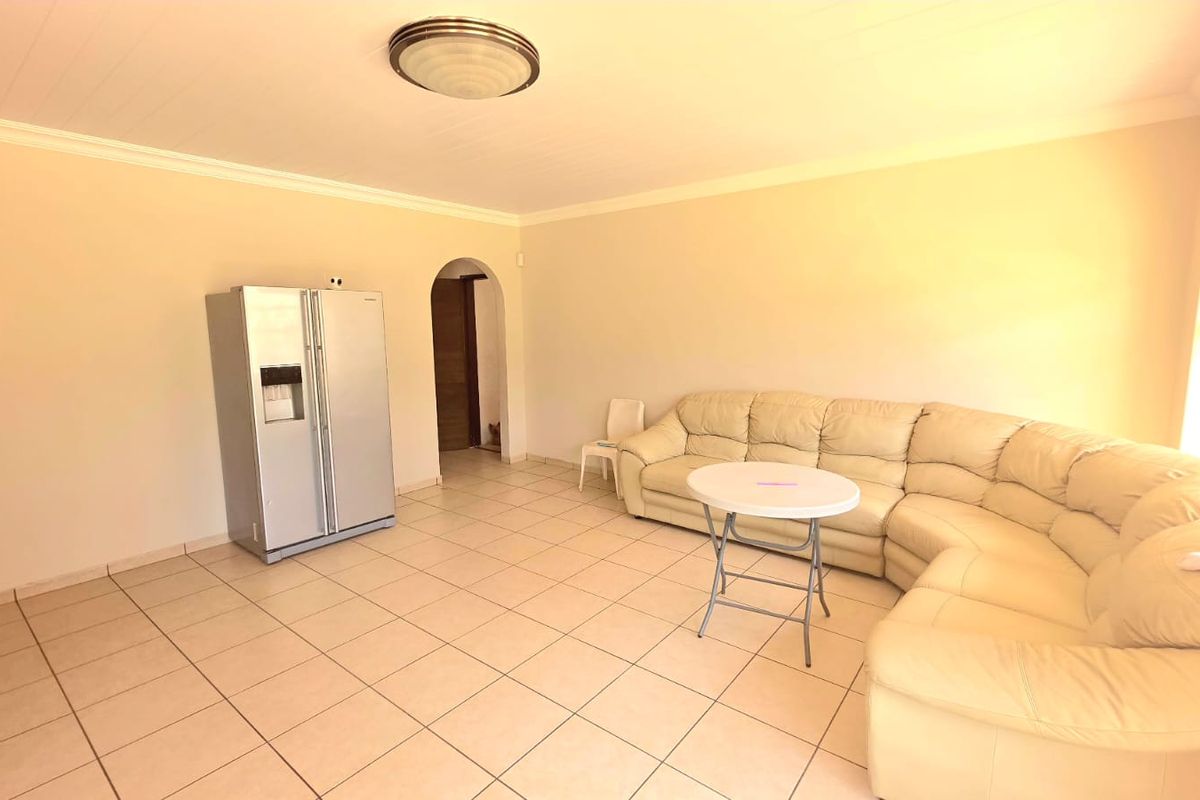 Spacious living area featuring neutral ceramic floor tiles, an arched doorway, and coved cornice detailing, providing a versatile foundation for interior design.
