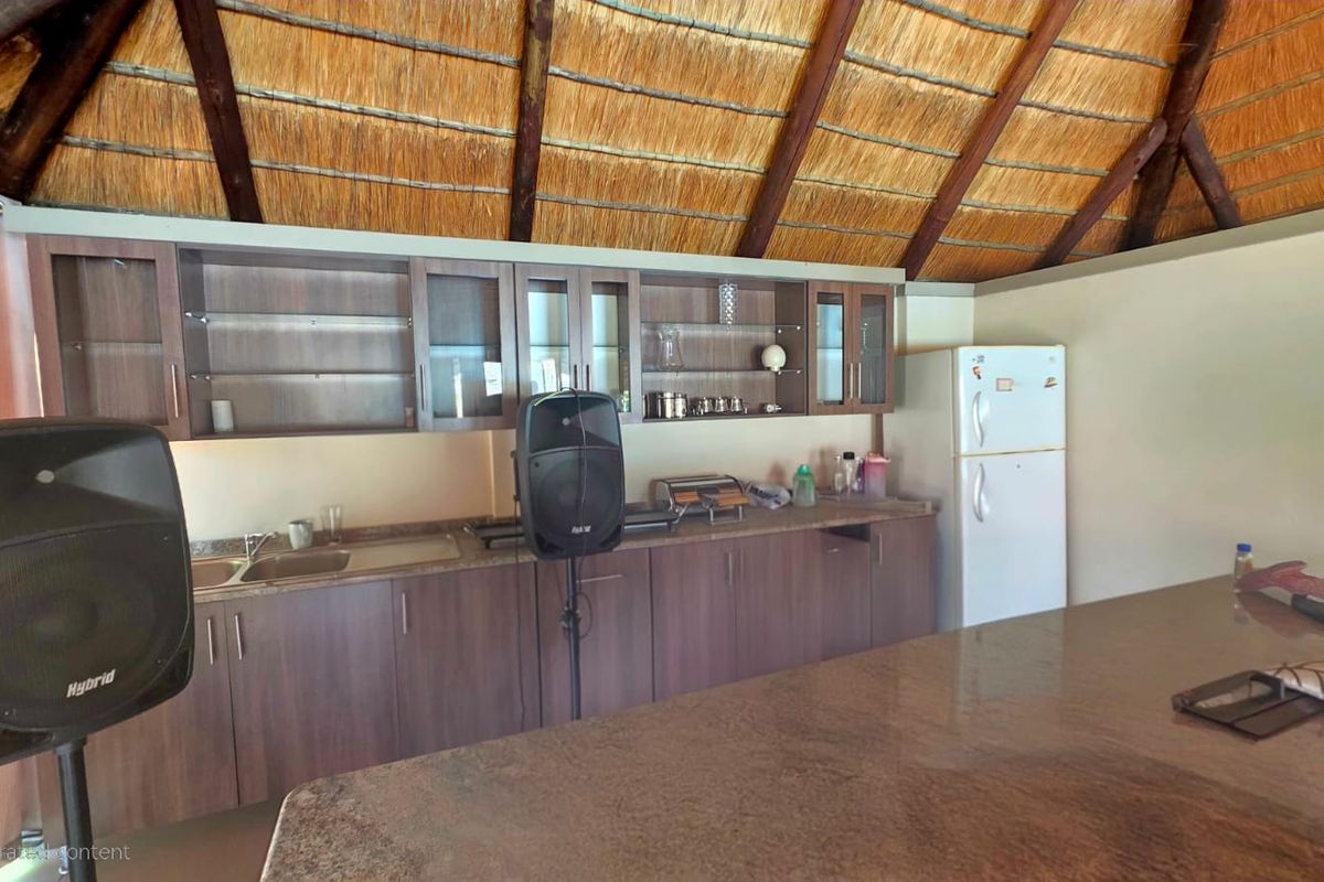 A kitchen area featuring dark wood cabinetry, granite countertops, and a distinctive exposed thatch roof ceiling.