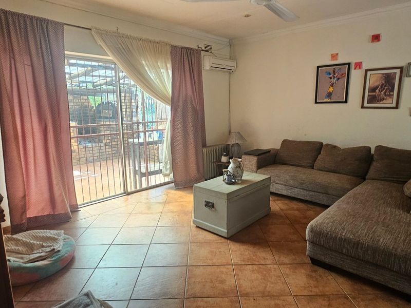 A comfortable living room featuring tiled flooring, a ceiling fan, wall-mounted air conditioning, and direct access to an outdoor patio area through sliding glass doors.