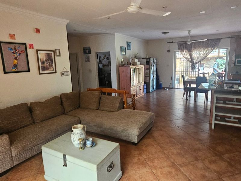 Spacious open-plan living and kitchen area featuring tiled flooring, ceiling fans, and a functional kitchen island, offering a versatile layout for family living.