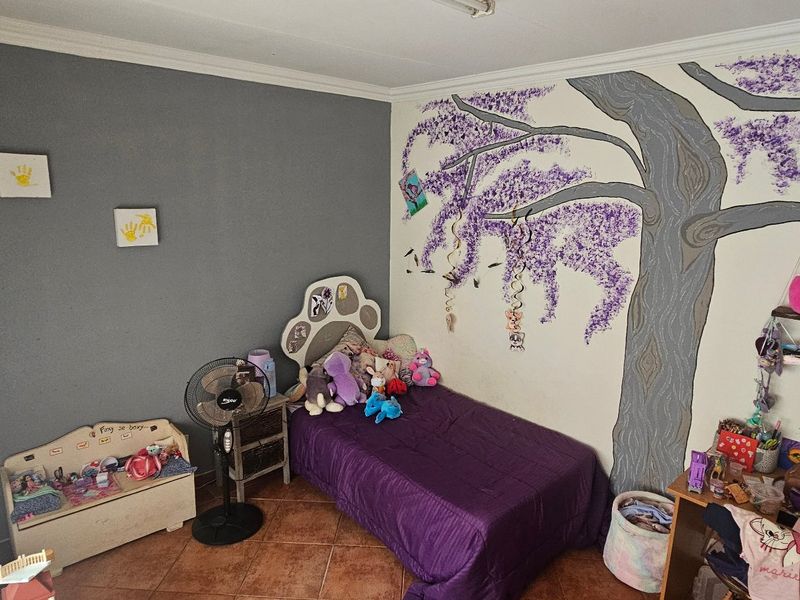 A bedroom featuring tiled flooring and decorative wall mural, providing a functional space with neutral grey and white wall finishes.