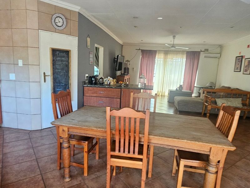Open-plan living and dining area featuring tiled floors, built-in kitchen cabinetry with integrated oven, and direct access to the patio area.