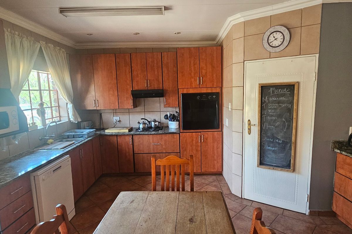 A functional kitchen featuring warm-toned wooden cabinetry, granite countertops, built-in oven, and tiled flooring, offering a classic layout with ample storage space.