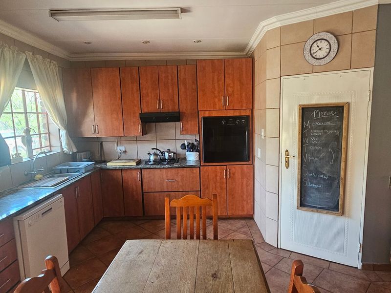 A functional kitchen featuring warm-toned wooden cabinetry, granite countertops, built-in oven, and tiled flooring, offering a classic layout with ample storage space.