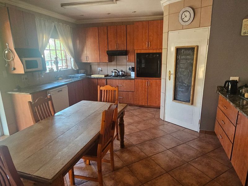 Open plan kitchen and dining area featuring wooden cabinetry, granite countertops, built-in oven, and direct access to an outdoor patio through sliding glass doors.