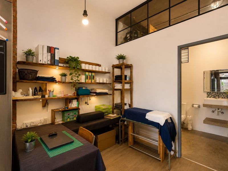 A functional utility space featuring exposed brickwork, custom shelving, and an adjoining bathroom with a modern wall-mounted basin and concrete flooring.
