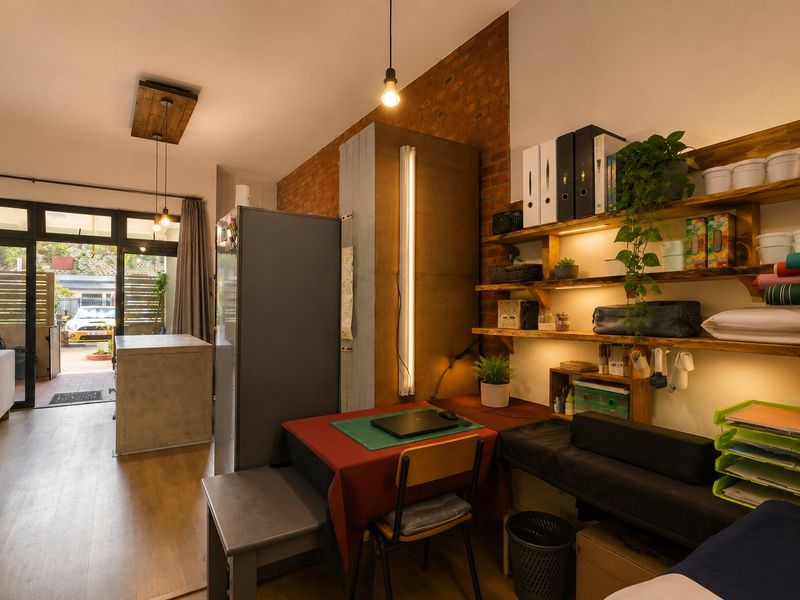 Open plan living area featuring exposed brickwork, laminate flooring, and direct access to an outdoor patio through sliding glass doors.