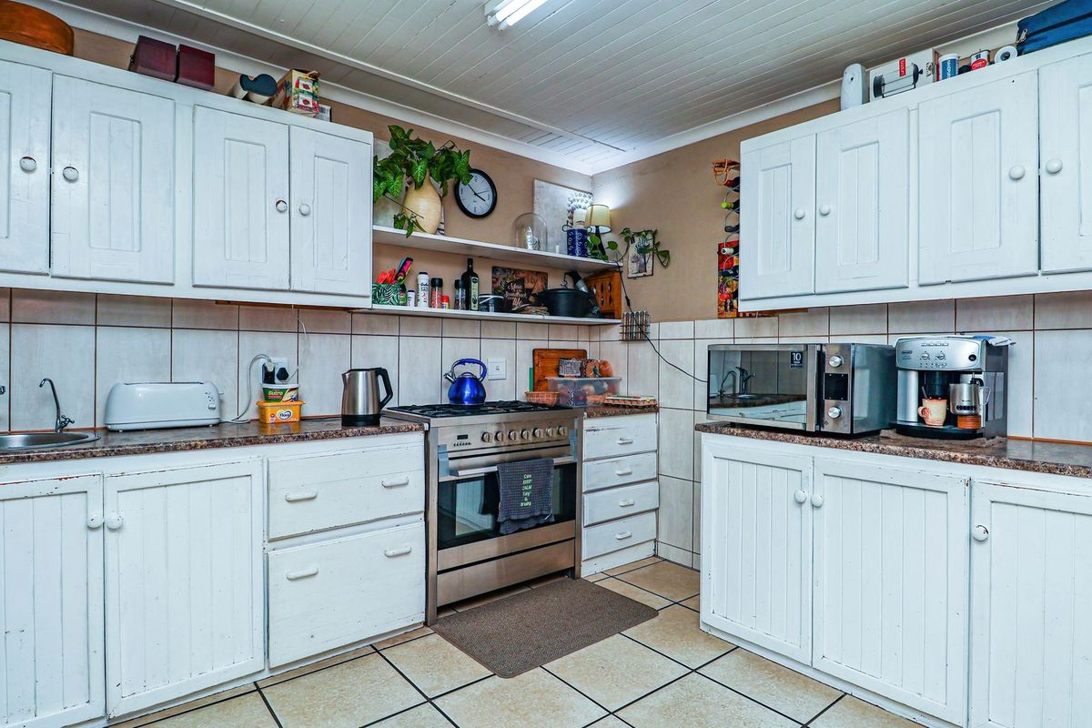 A functional kitchen featuring white built-in cabinetry, stainless steel gas stove and oven, tiled backsplash, and tiled flooring.