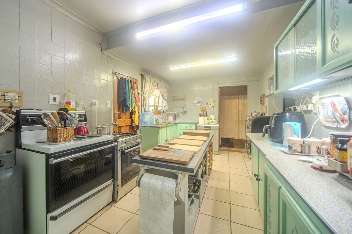 A functional kitchen featuring tiled walls and flooring, built-in cabinetry, and a gas stove, offering potential for a modern renovation.