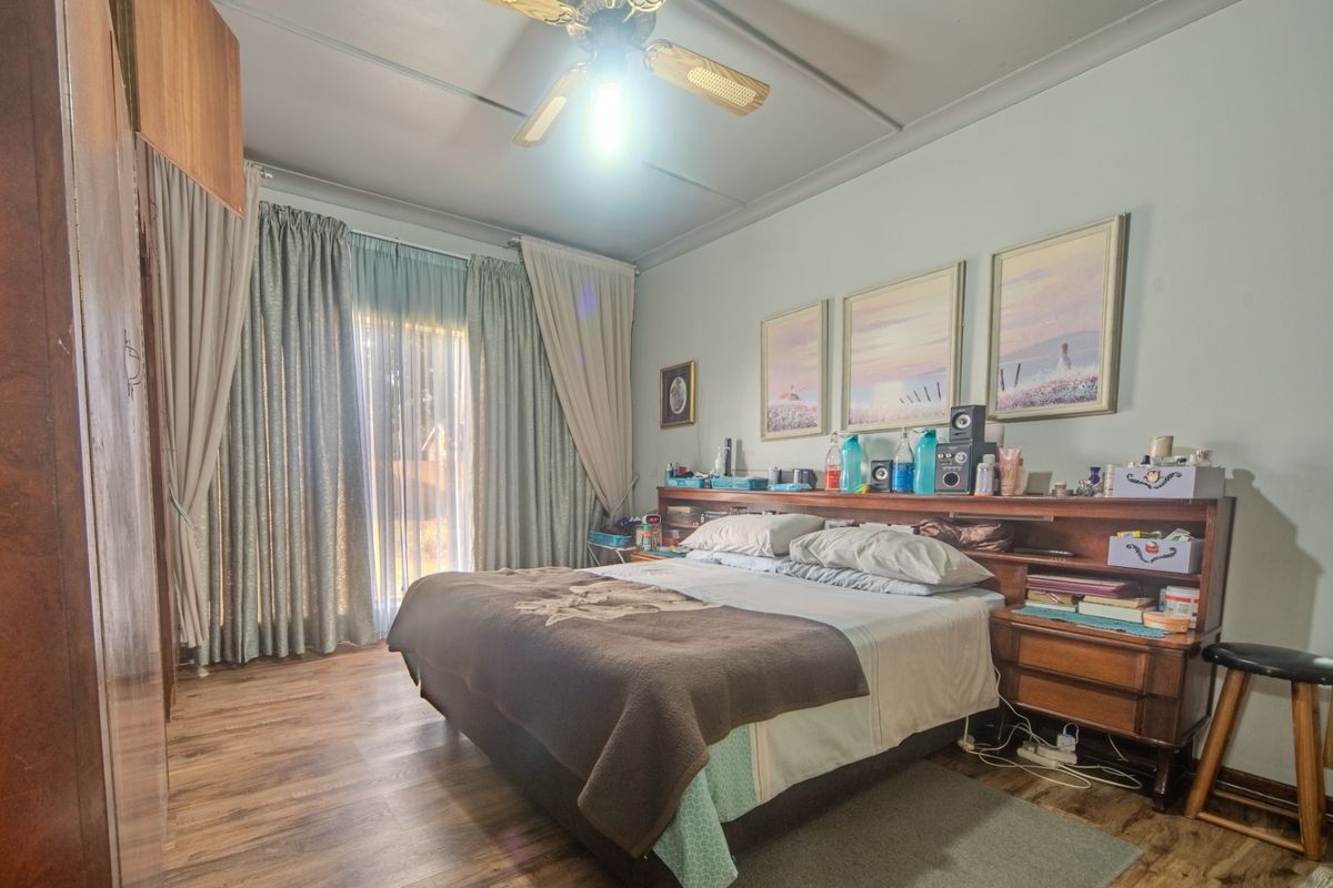 A bedroom featuring laminate flooring, a ceiling fan, and a sliding glass door providing access to the exterior.