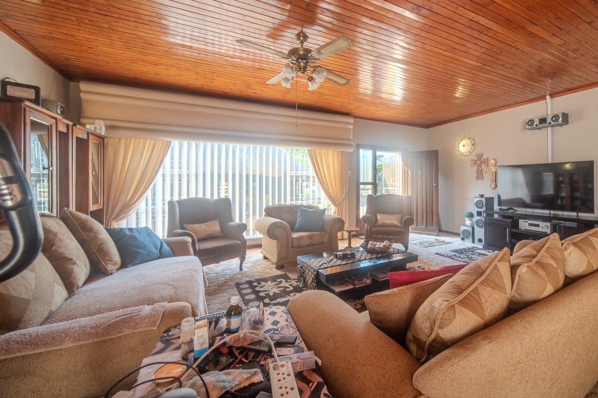 Spacious living room featuring a warm timber tongue and groove ceiling, ceiling fan, and large sliding glass doors providing access to the exterior.