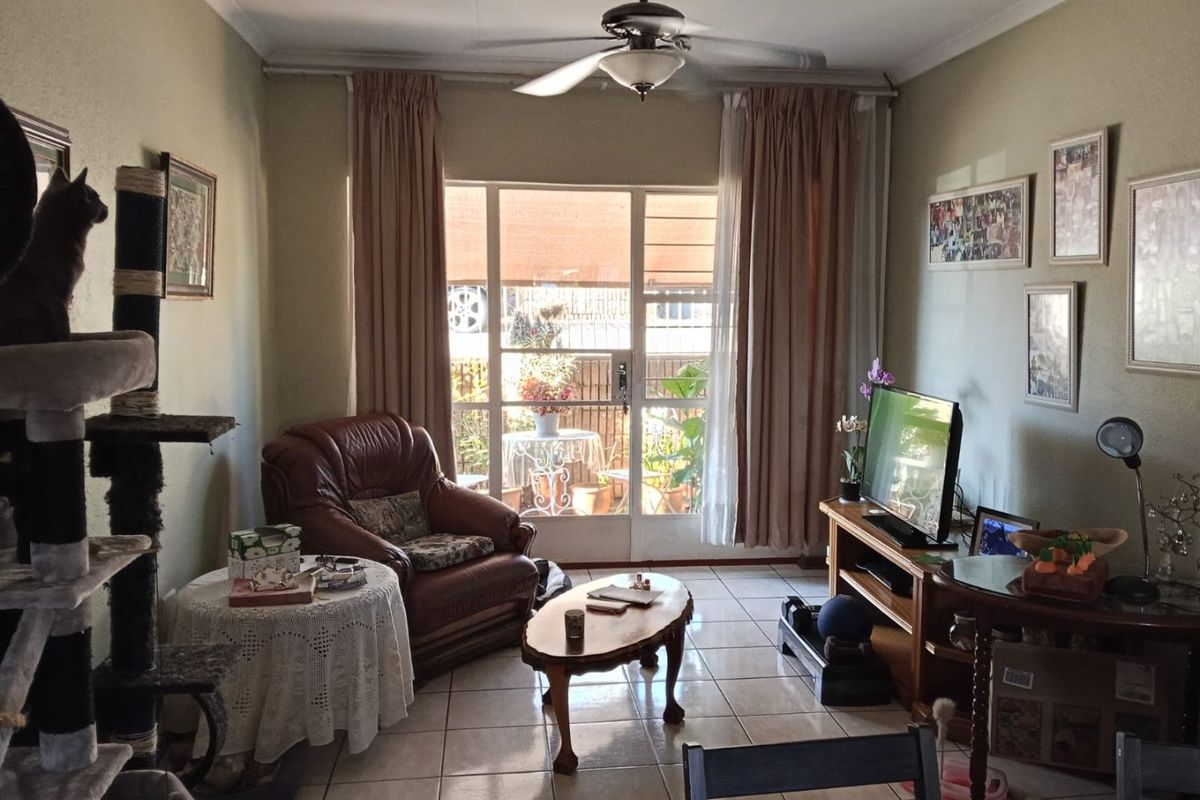 A comfortable living room featuring tiled flooring, a ceiling fan, and a sliding glass door providing access to the outdoor area.