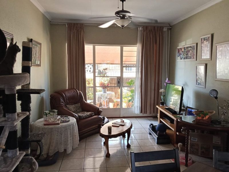 A living room featuring tiled flooring, a ceiling fan, and a sliding glass door providing access to the outdoor area.
