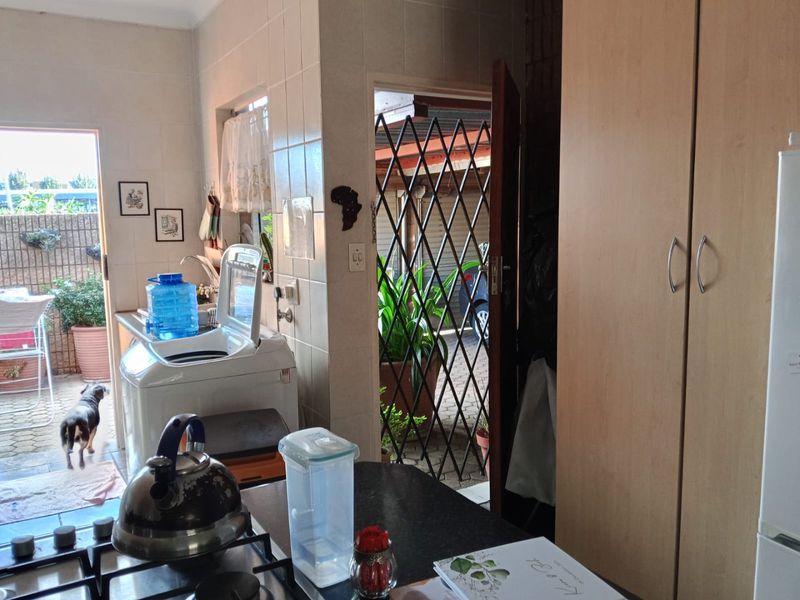 A functional laundry area featuring built-in cabinetry and tiled walls, with direct access to an outdoor patio space.