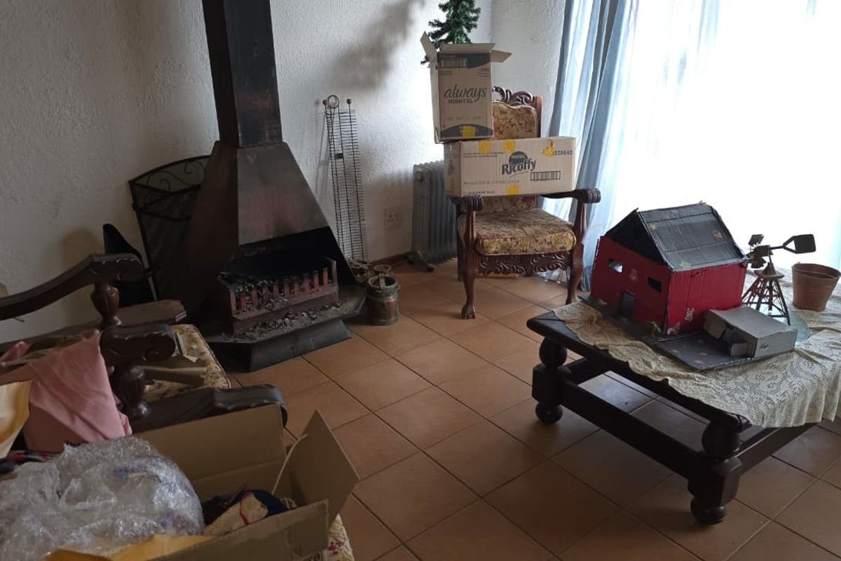 Living room featuring a traditional freestanding fireplace and tiled flooring, offering a functional space with potential for cosmetic updates.